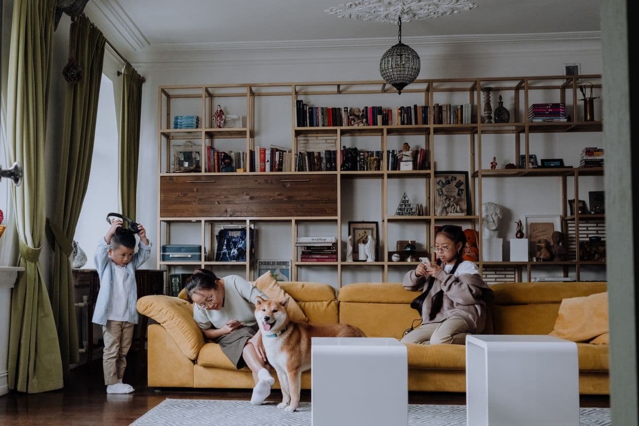 Eine Familie sitzt mit ihrem Hund gemeinsam im Wohnzimmer